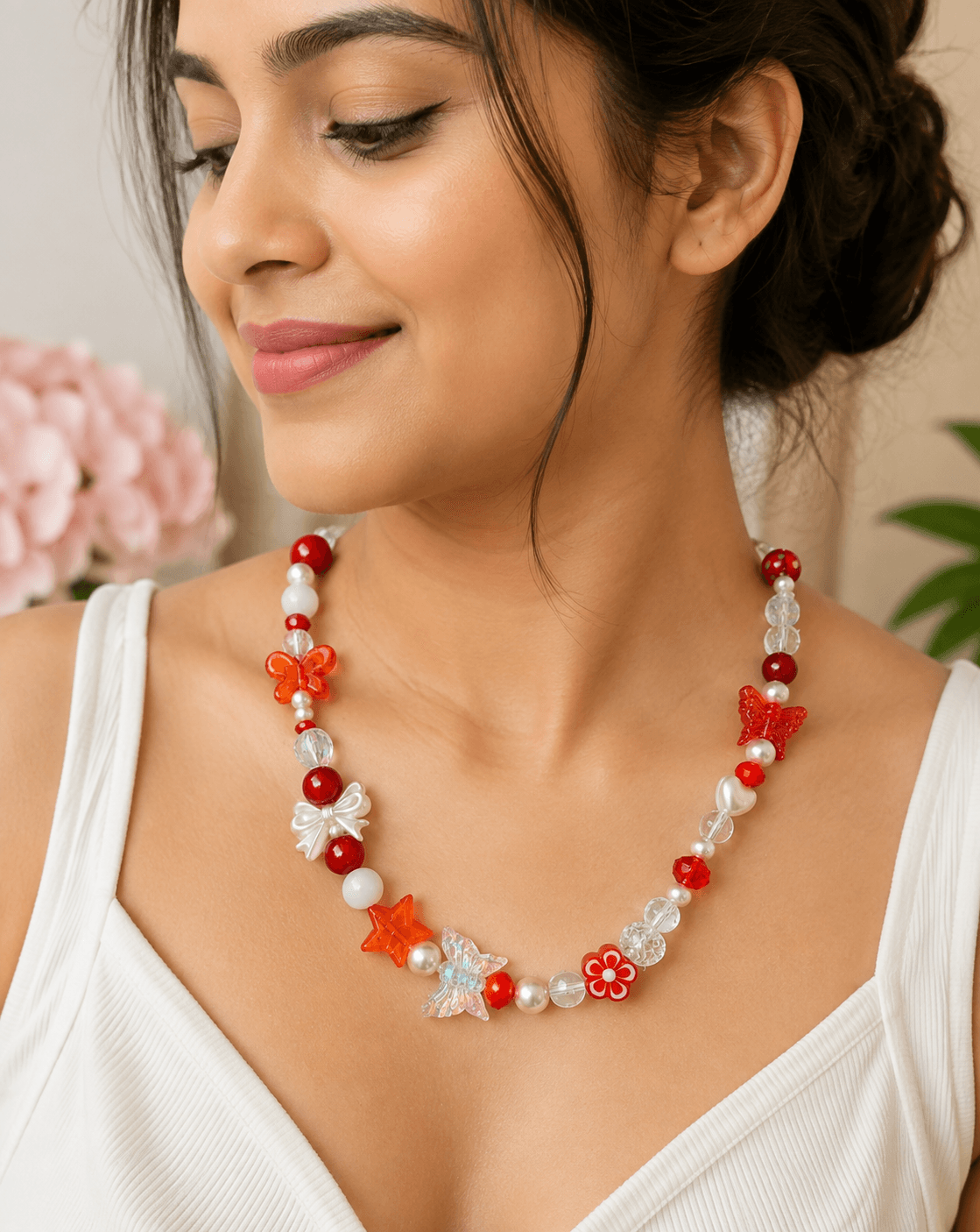 Woman wearing a handmade red butterfly beaded necklace with colourful butterfly, flower, bow and star details over a white outfit.