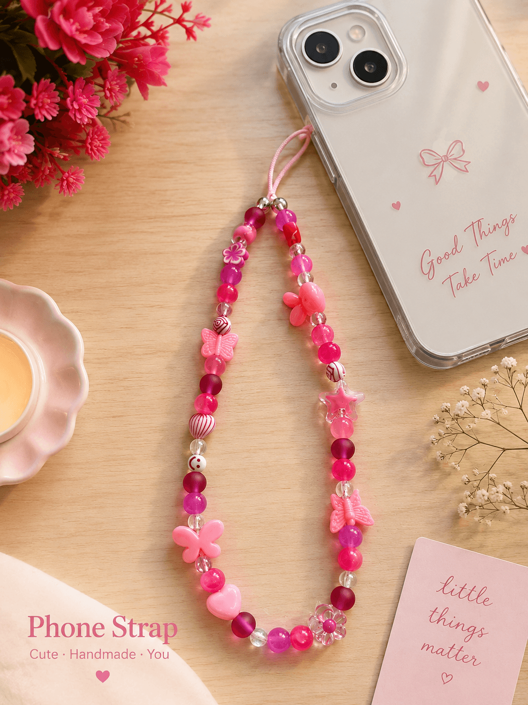 Pink handmade beaded phone strap with butterfly, flower, heart and star beads displayed beside a clear phone case.