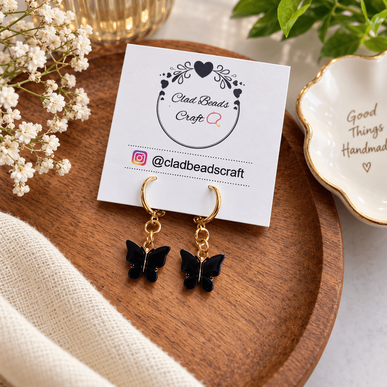 Pair of deep-blue butterfly dangle earrings with gold-tone hoops displayed on a Clad Beads Craft card