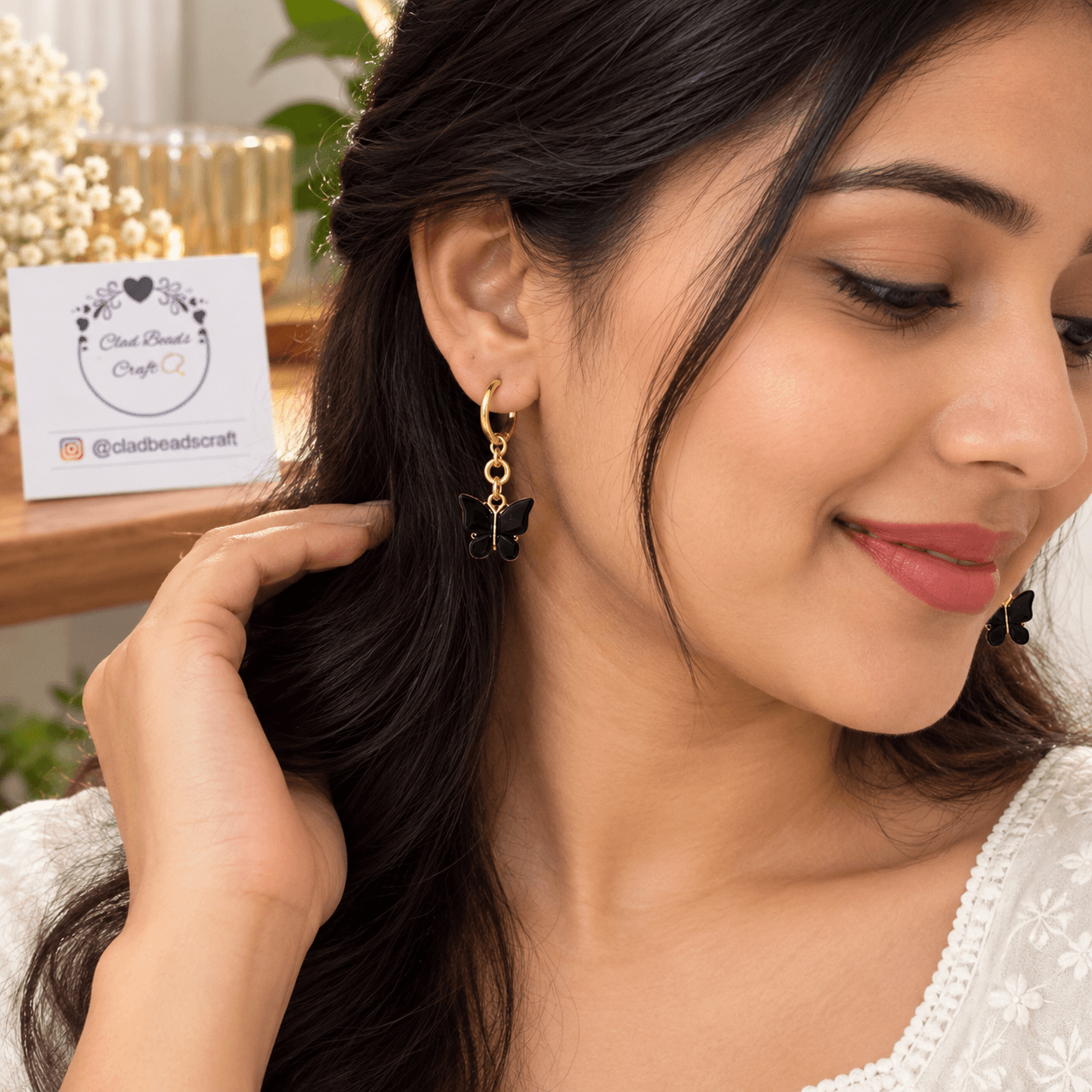 Woman wearing a deep-blue butterfly dangle earring with a gold-tone hoop