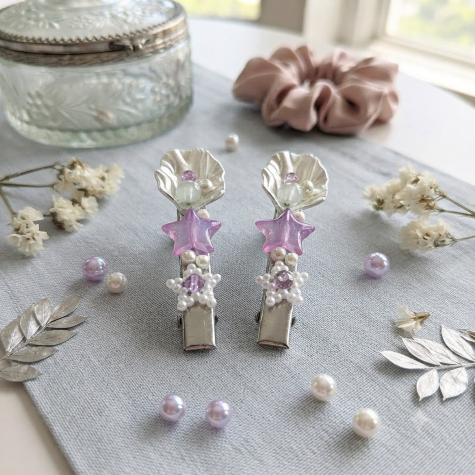 Two pastel purple and mint beaded hair clips displayed on a soft fabric surface